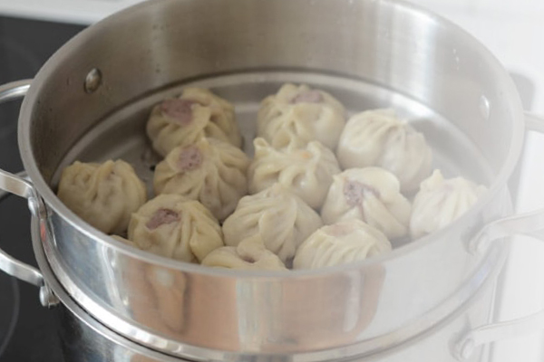 Freshly steamed dumplings sit inside a large pot.