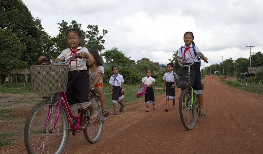 A school girl rides her bike to school with her friends in Laos.