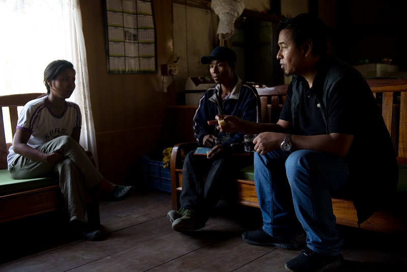 A humanitarian worker sits with a couple in a dim room.