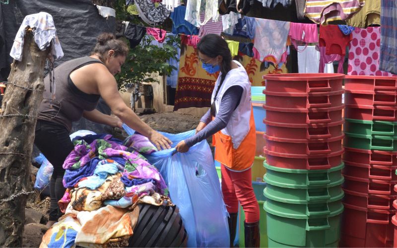 Two women put clothing into bags for distribution.
