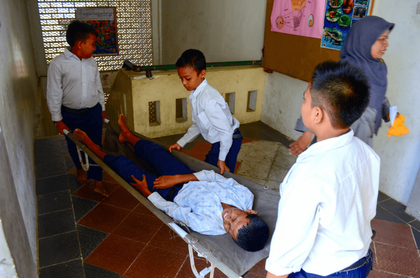 Children do an earthquake preparedness drill at school, carrying a fellow student in a stretcher.