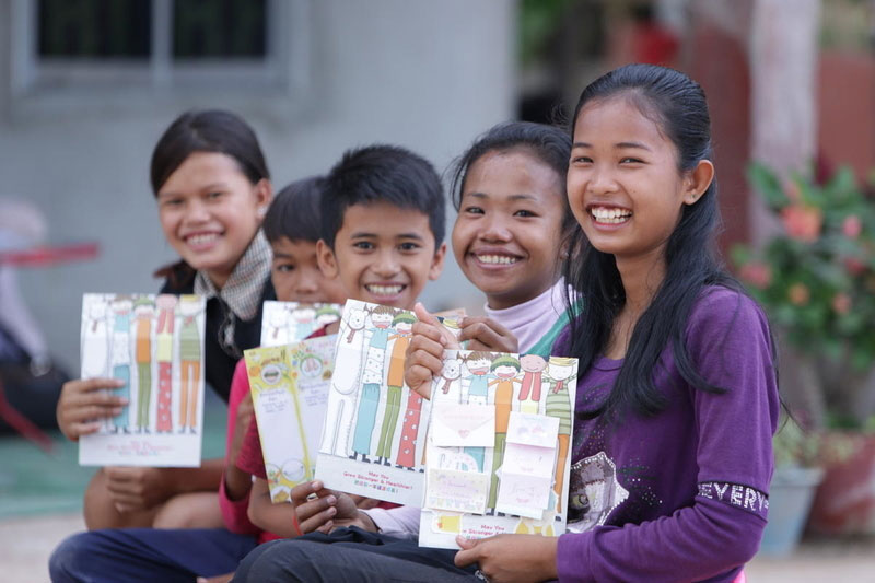 Five children from Cambodia show off colorful Christmas cards.