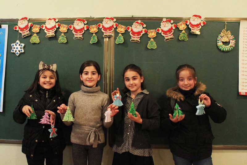 Four school aged girls show Christmas crafts they made.