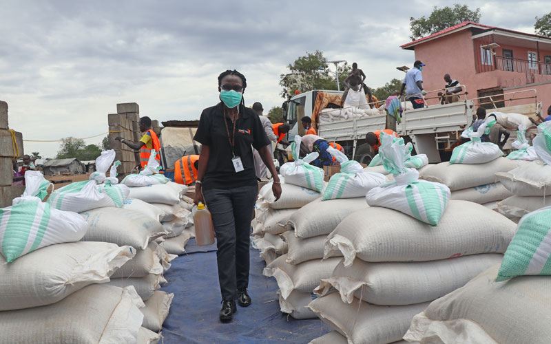 A Rwandan woman walks between bags of food assistance