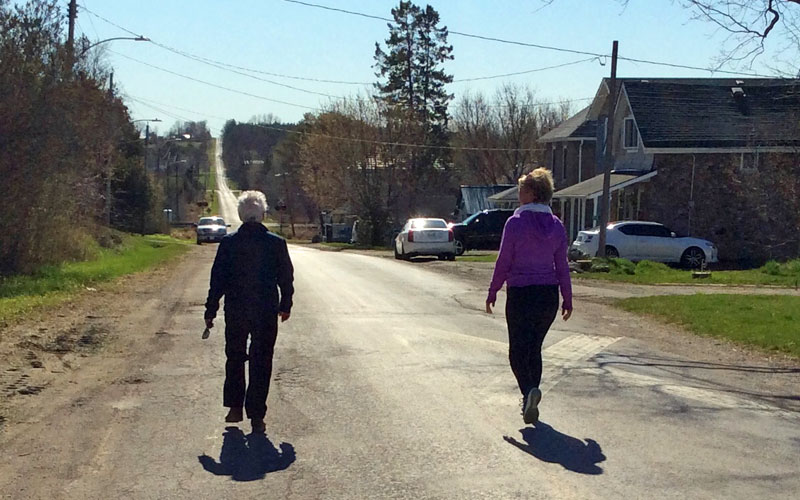 Two Canadian women walking down a country road.