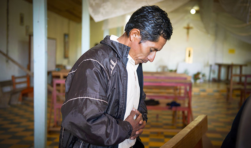 In Honduras a man prays with his head bowed in a church