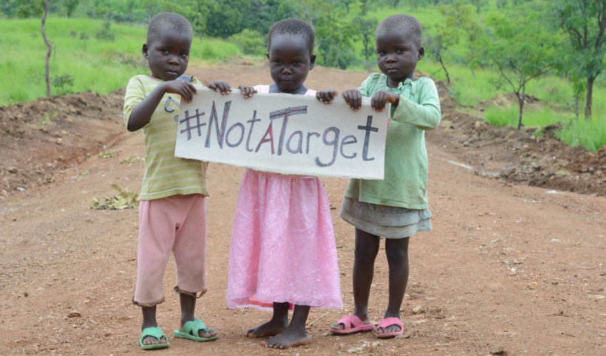 three small children hold a sign that says #NotATarget