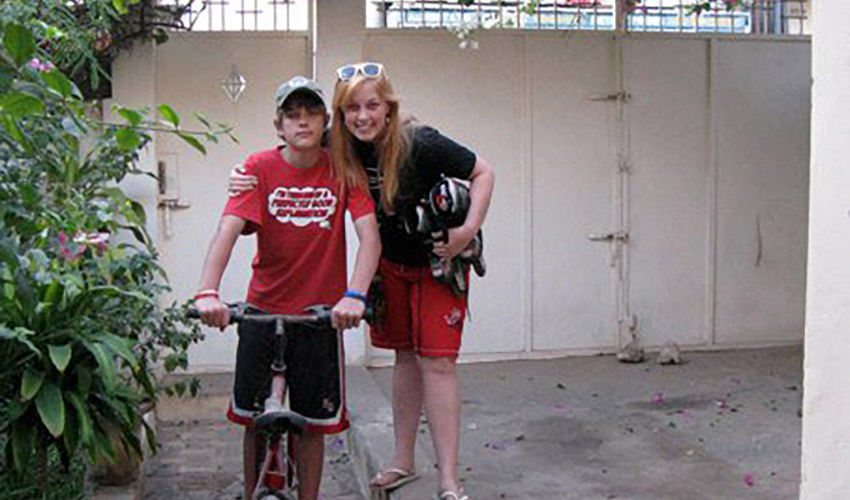young woman with arm around her little brother who is sitting on bicycle