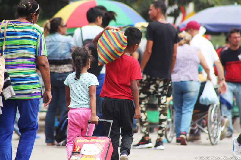children and parents walk carrying heavy bags