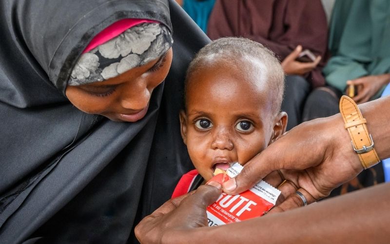 An infant is being fed Ready-to-Eat Therapeutic (RUTF) by World Vision staff in the Darussalam Mother and Child Health Center in Baidoa, Somalia.