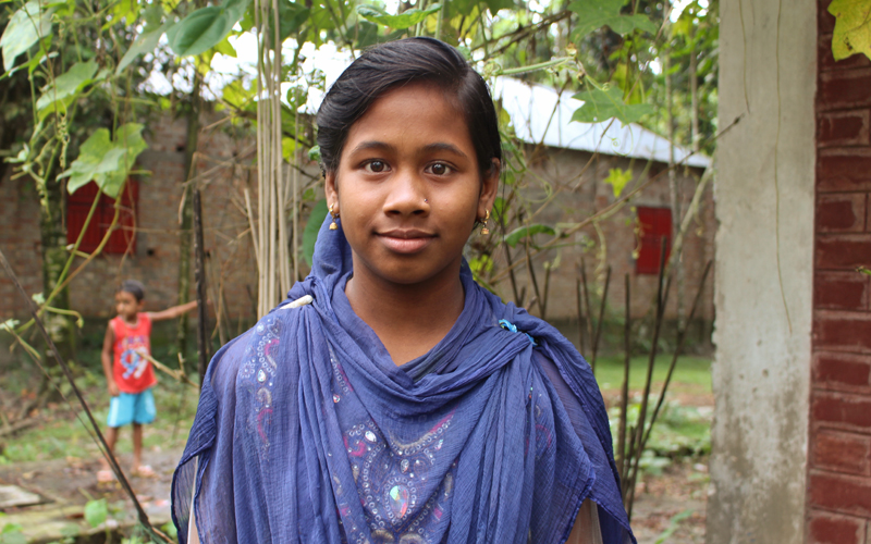 a young Bangladeshi girl poses for the camera in a blue scarf and dress.