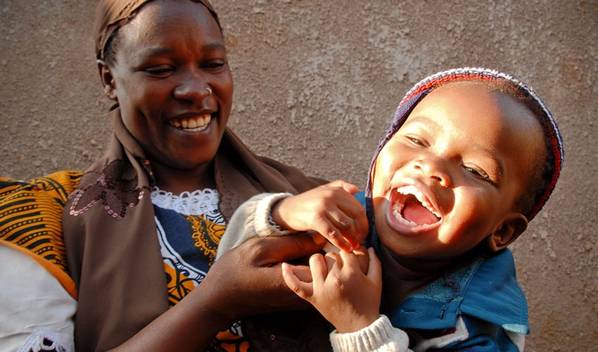 In Kenya a mother tickles her toddler age daughter while she laughs hysterically.