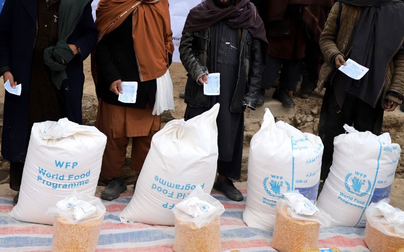 Cropped photo showing a row of men standing in a row to claim food rations.