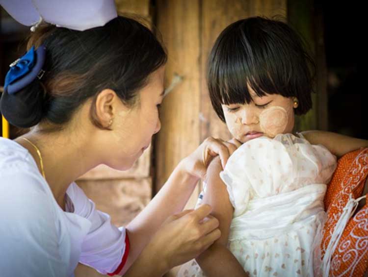 A trained auxiliary midwife vaccinating a child on her arm.