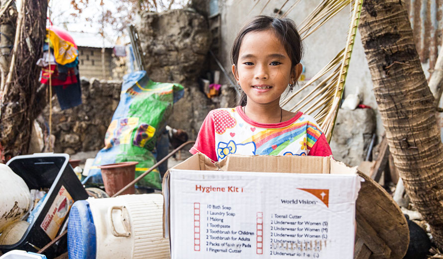 Girl carrying a hygiene kit from World Vision.