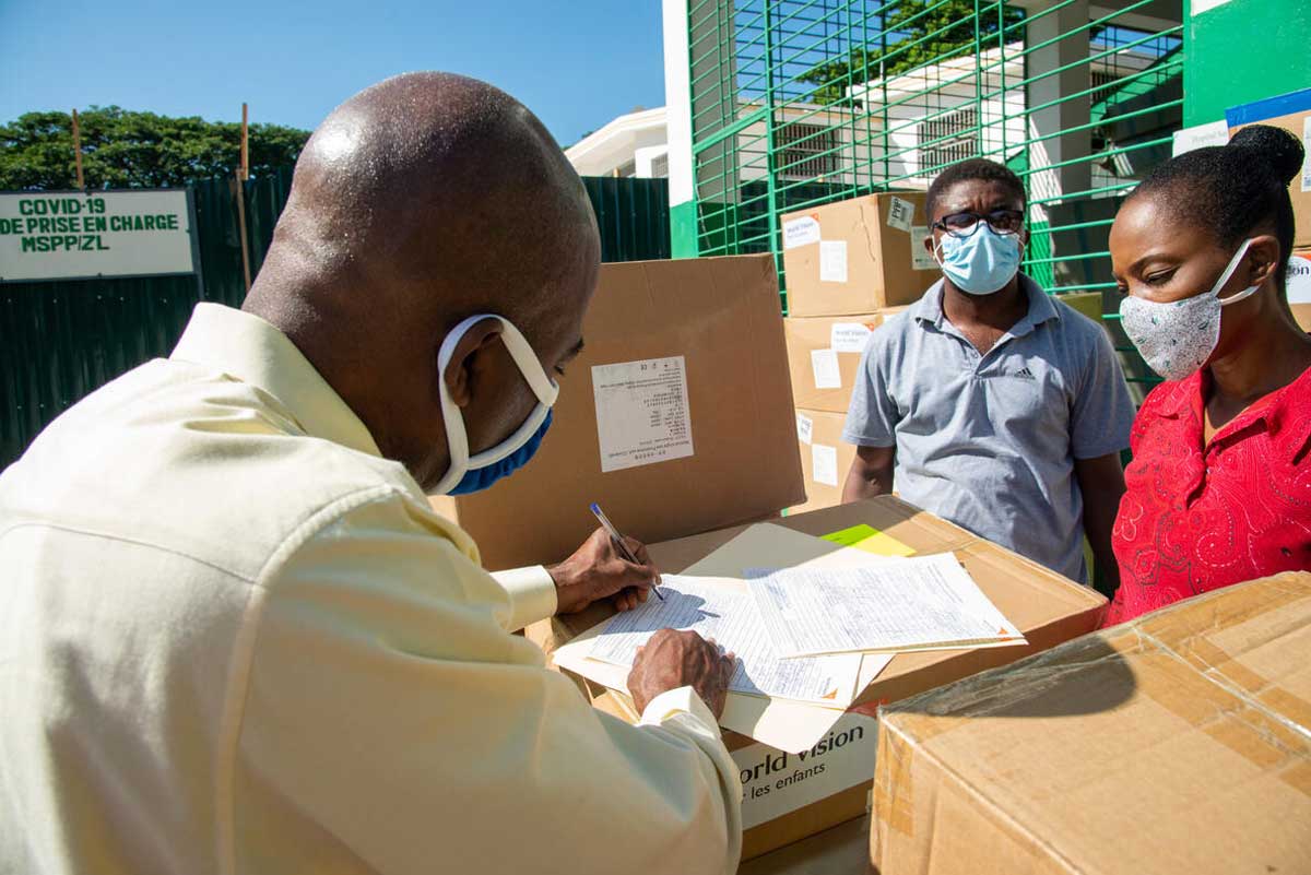 An official wearing a mask inspects medical supplies arriving at the Sainte-Thérèse Hospital in Haiti, provided by World Vision Haiti.