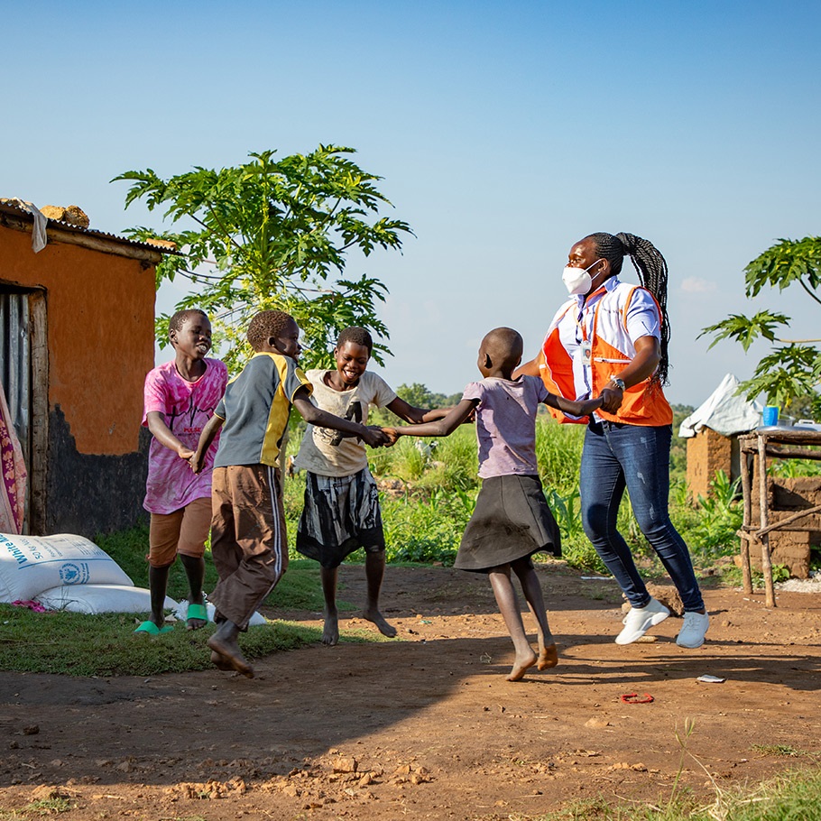 Four children playing around in a circle with a World Vision staff.