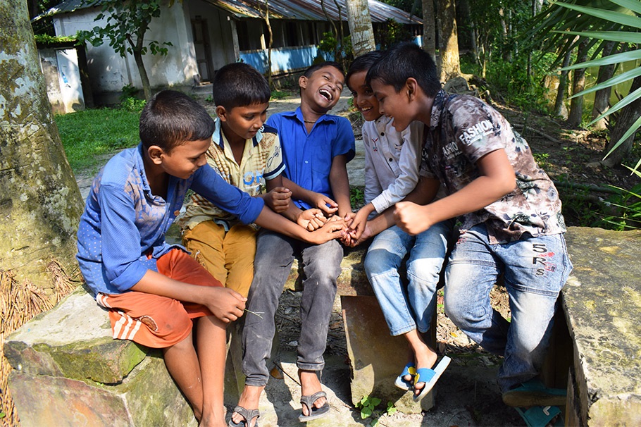 A group of boys sitting alongside each other, laughing.