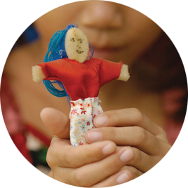 a close-up of a young girl holding up a small, hand-made doll