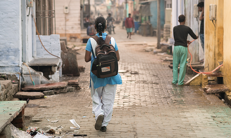 young girl walks through an alley with a World Vision backpack