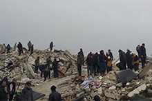 Men standing on rubble, some lifting large pieces of concrete