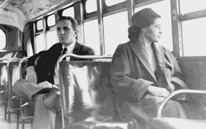 A crowd of workers, adults and children, carry signs pressing for measures like unemployment insurance.A Black woman sits in a seat near the front of a bus, hands folded, looking out the window. Behind her sits a white man.