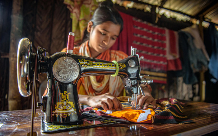 In Bangladesh, a teenaged girl works on a sewing machine.