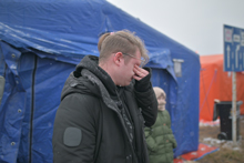 A man in a black jacket wipes his tears.