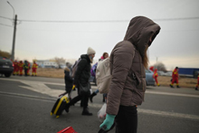 Ukranian refugess wearing winter gear walk along the streets of the Romanian border.