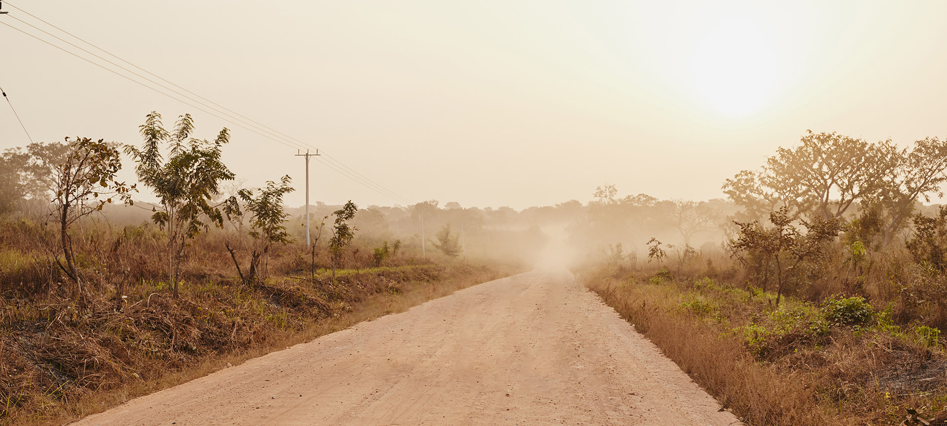 A dusty dirt road stretches for miles along the countryside. 
