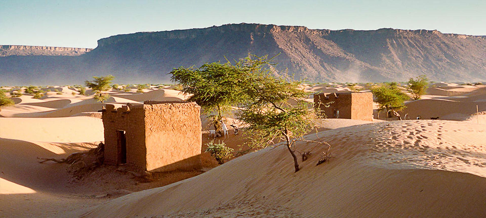 A desert area with two building structures standing 