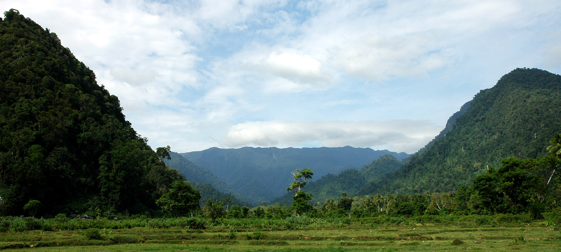 A Lush green area with mountains and hills surrounding. 