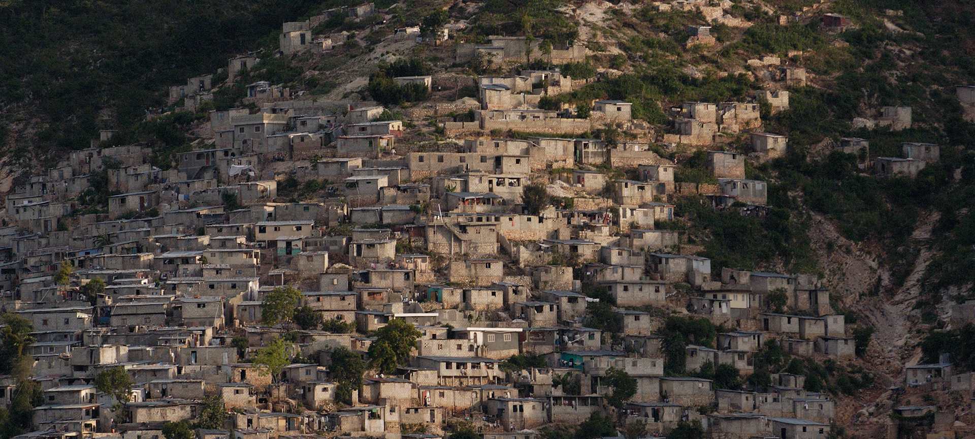 Small brown buildings situated along a green mountainside