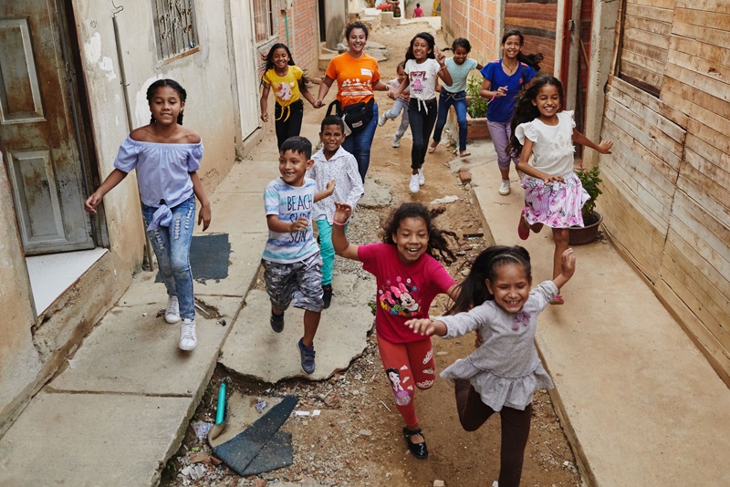Children of various ages running in an alleyway.