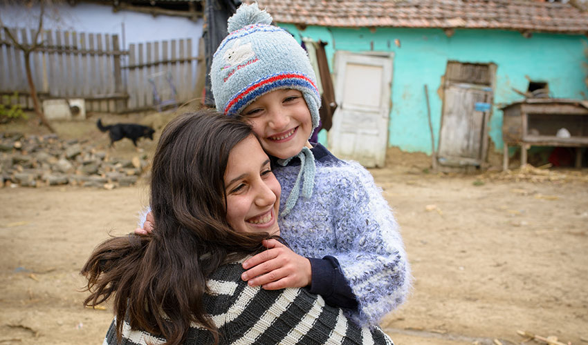 young brother and sister hugging and smiling in romania