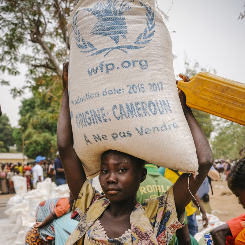 A woman in Central African Republic carries a bag of emergency food on her head.