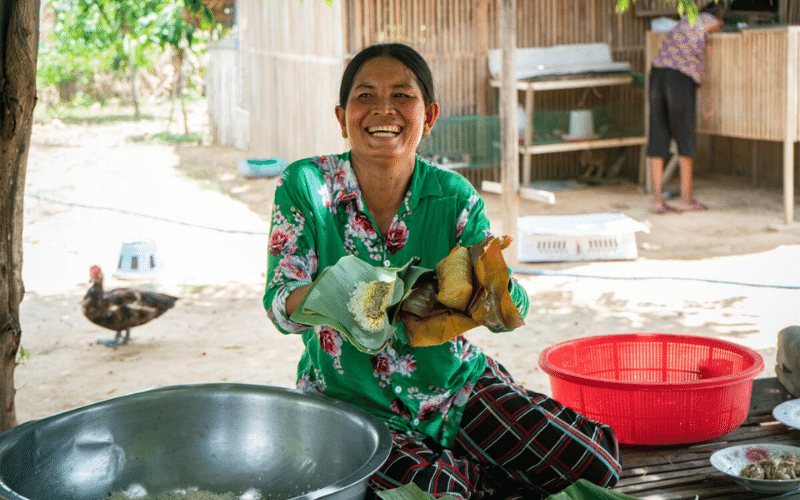 Sum Mon, a Cambodian woman, makes rice cakes in banana leaves, holding them open in her hands.