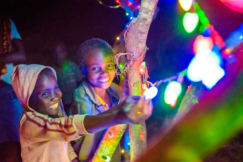 Two children from Zambia smile as they gaze at Christmas lights.