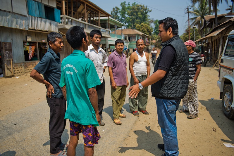 A humanitarian workers speaks with men in the street of a town.