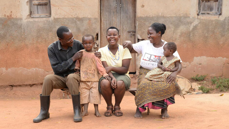 Juliet and her family are sitting on a bench in front of their home. From left to right is her father, her brother, Juliet, her mother and her sister.