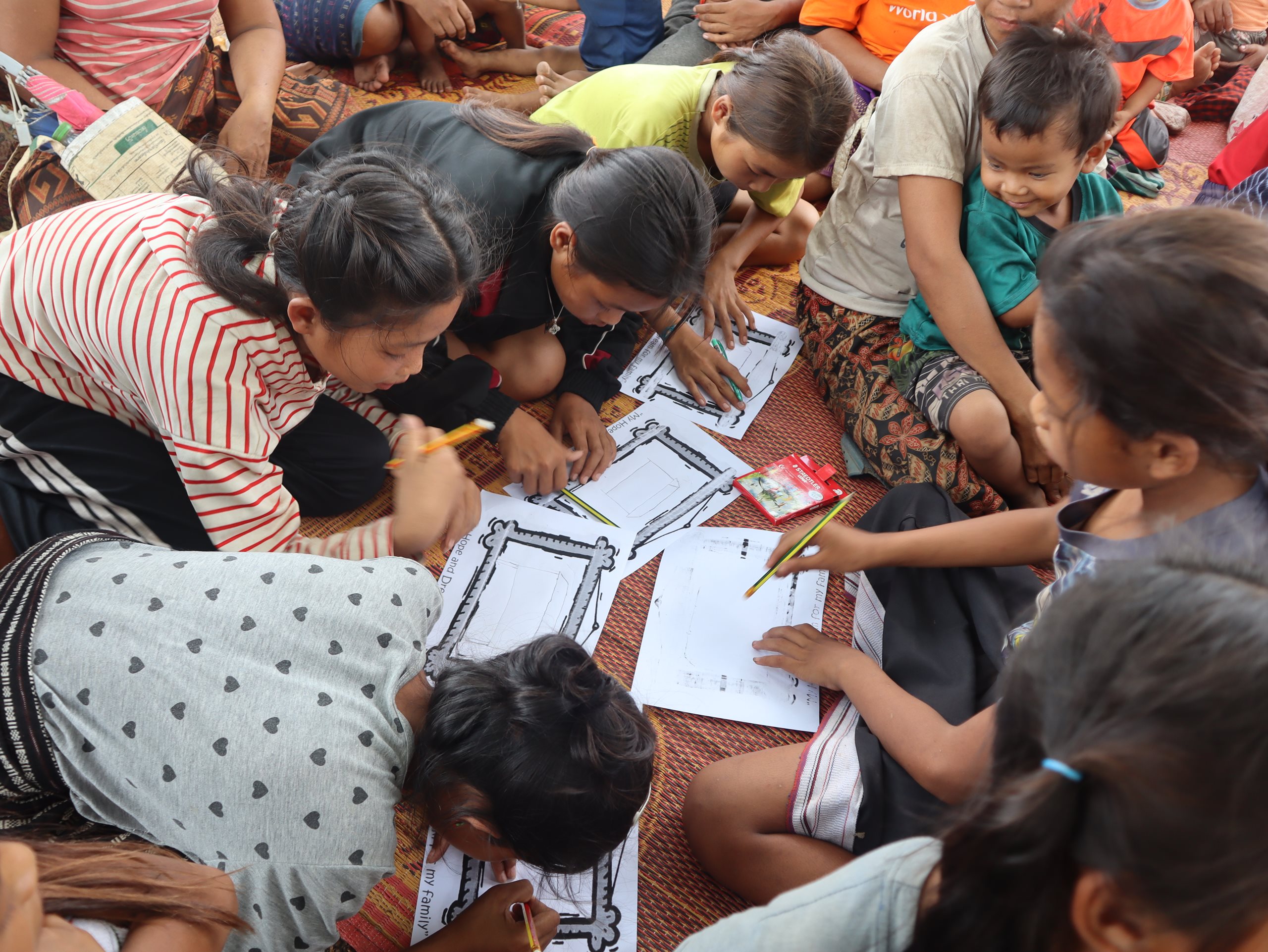 Children gather to participate in a drawing activity.