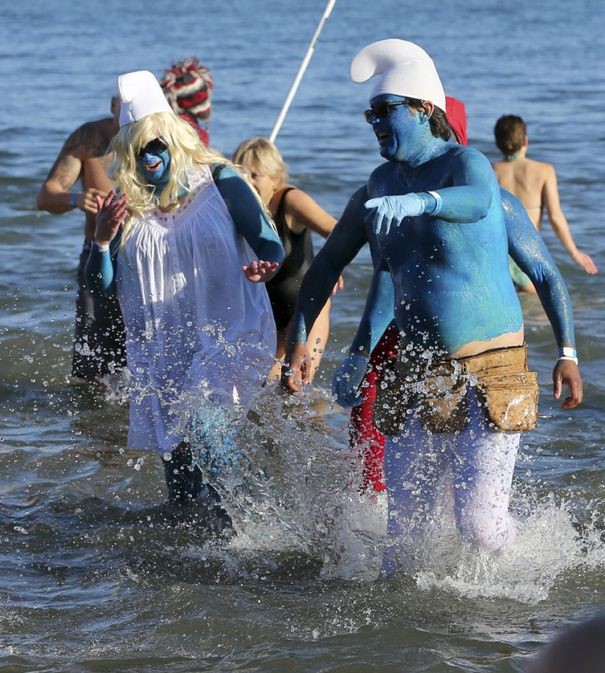 People dressed up like the Smurfs walk out of a lake during a polar plunge event.