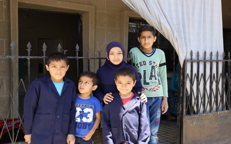 Five siblings, who are refugees from Syria stand in front of their home in Lebanon.