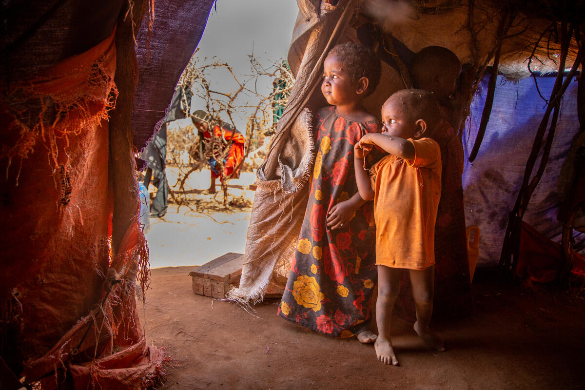 In a camp for people who have fled their homes to stay alive, two children from Somalia stare out the opening of their tent.