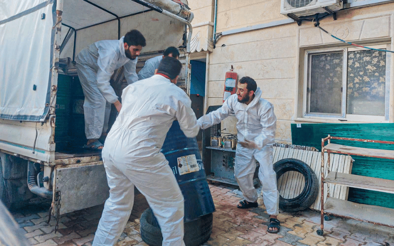 Four humanitarian staff help transport a cannister of fuel onto a truck for survivors in Syria.