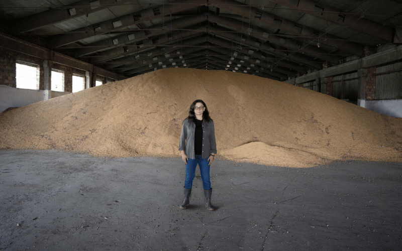 Lily stands in front of a massive pile of soya beans in her barn.