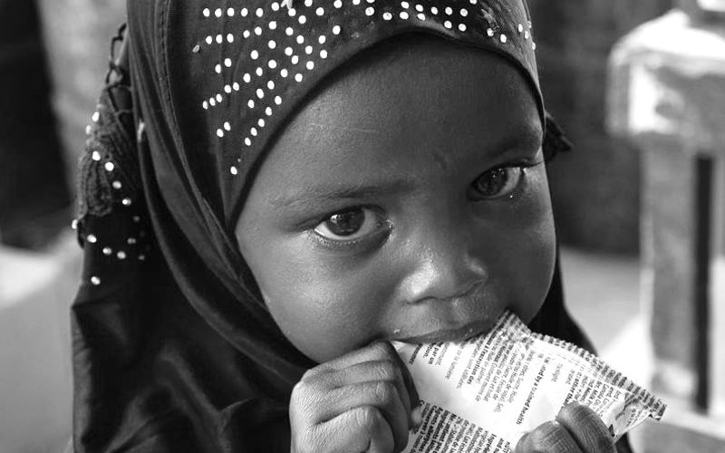 A tiny girl from Somalia, a toddler, eats from a package of ready to use therapeutic food