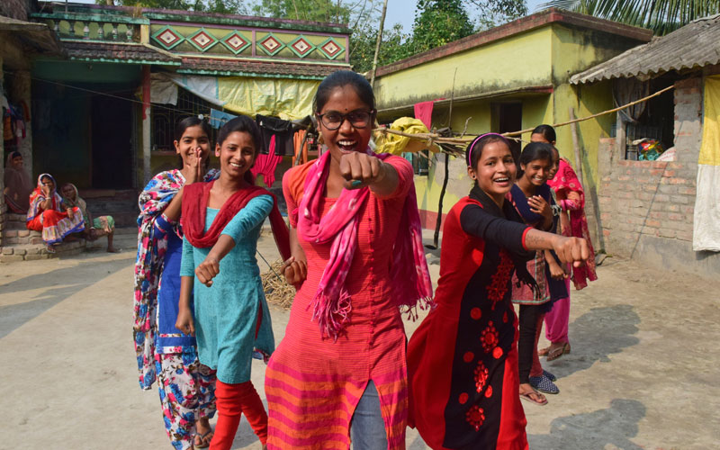 a group of Indian girls stand with fists out looking confident and happy.