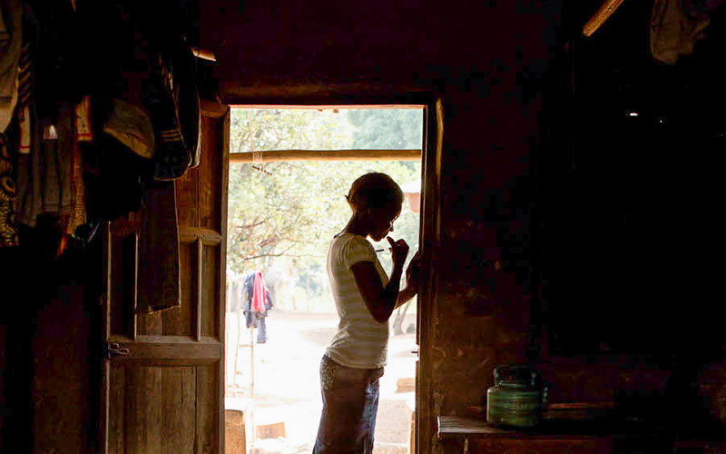 A young girl from Sierra Leone stands in a doorway