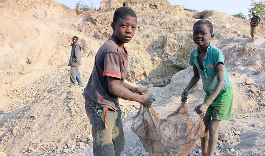 Two young boys who are child labourers lift sacks of dust in a copper mine